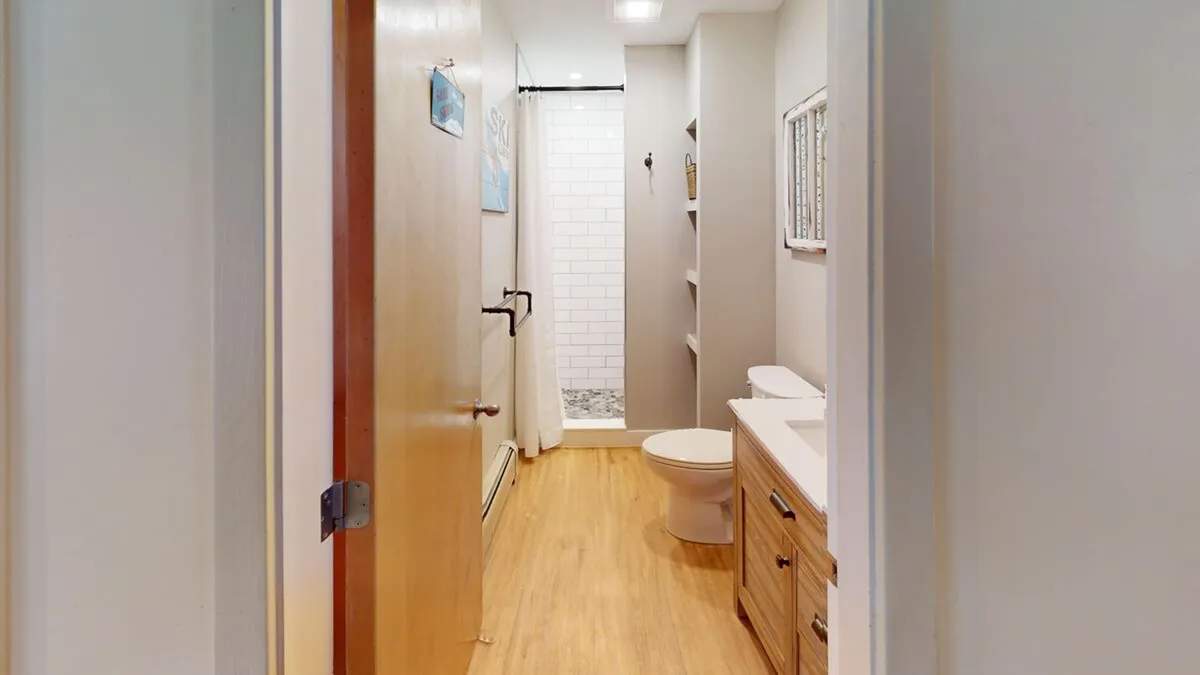 A modern, serene bathroom with a clean shower area, sink, and natural wood cabinetry. The calming mood and private setting evoke the personal renewal and self-care focus associated with full-service spa experiences.